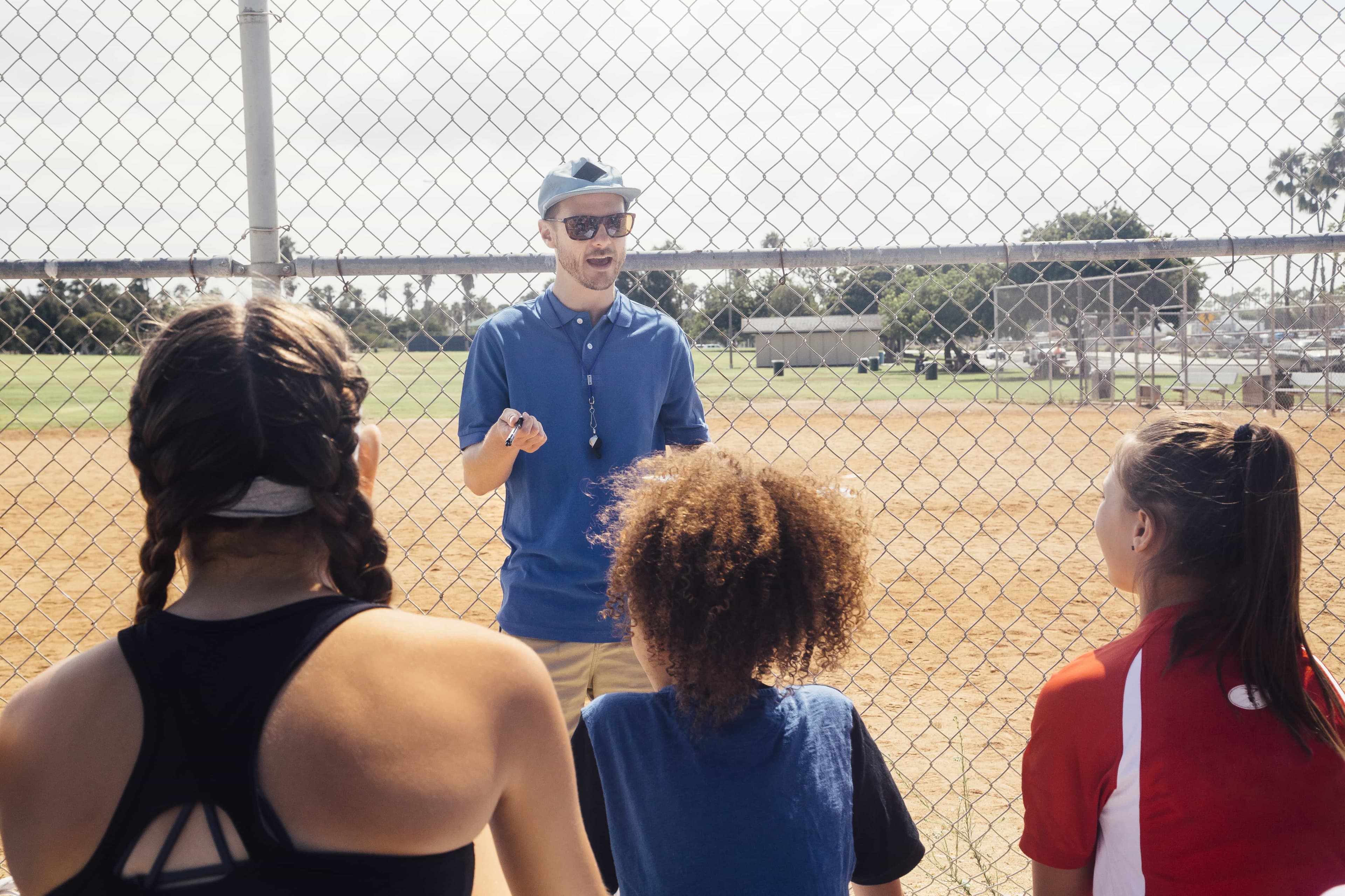 Coach teaching young athletes on a softball field